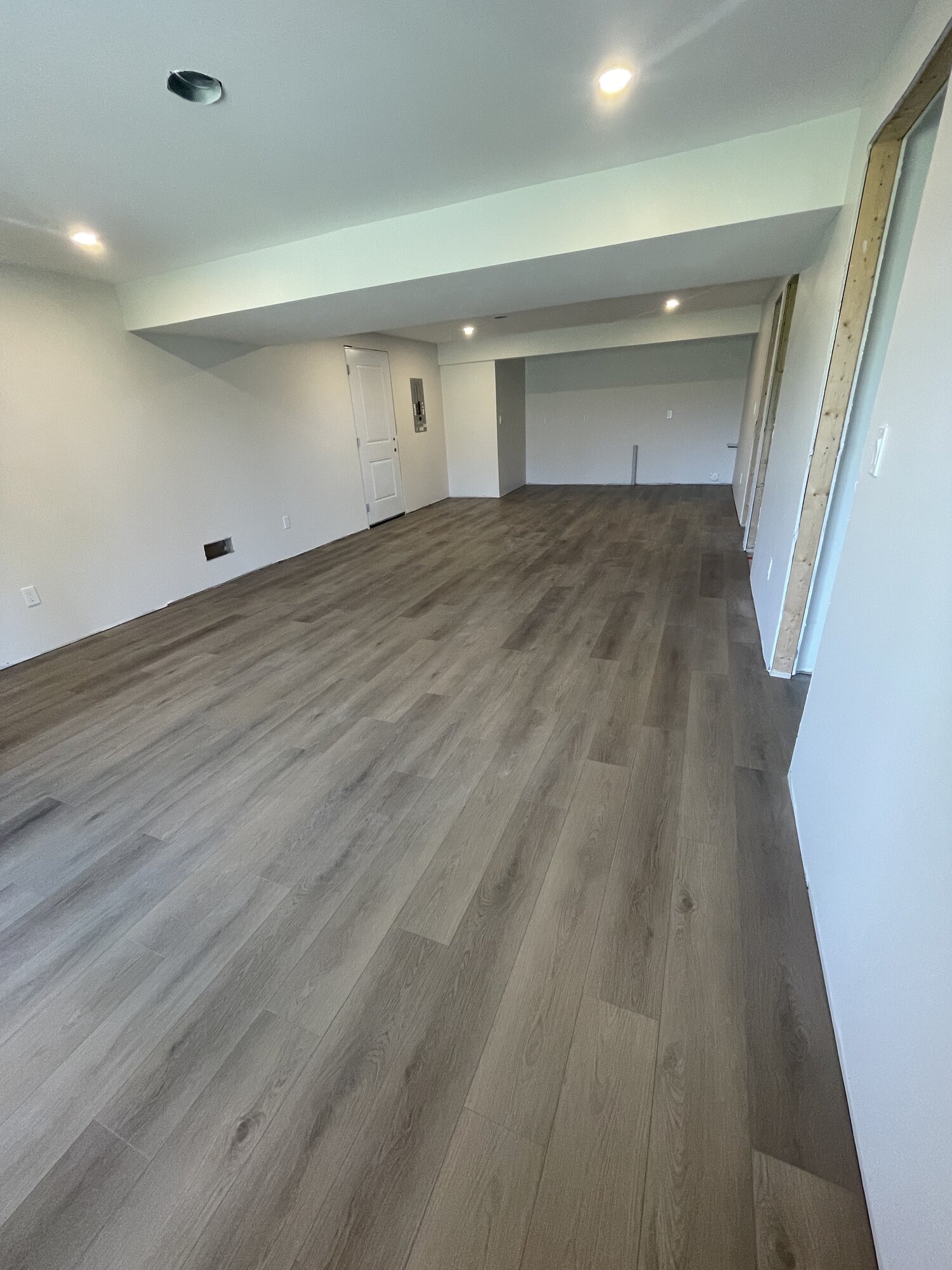 The same basement with a finished grey plank floor laid the length of the room.