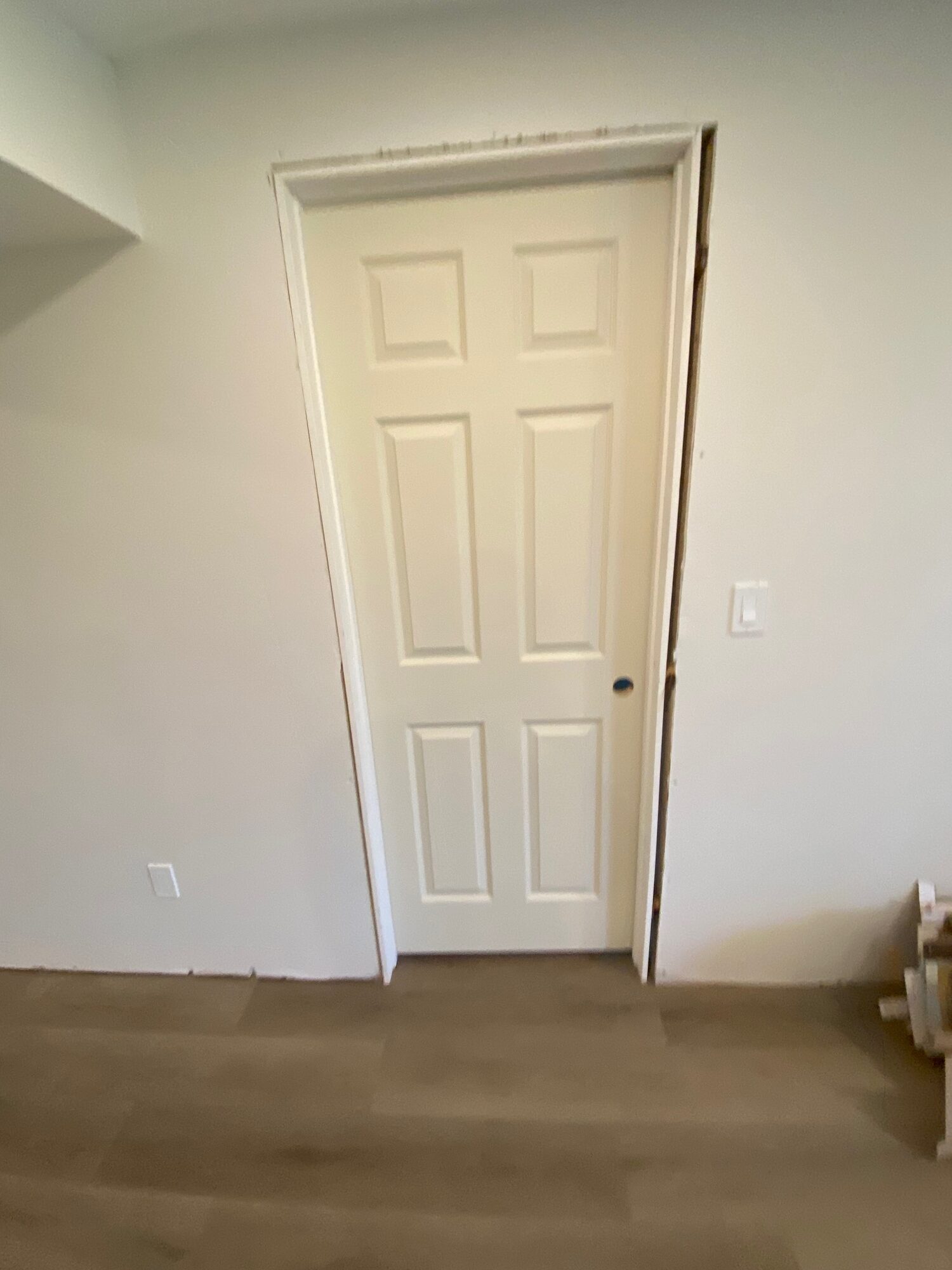 A new white six panel door, cased in white trim, above a plank floor.