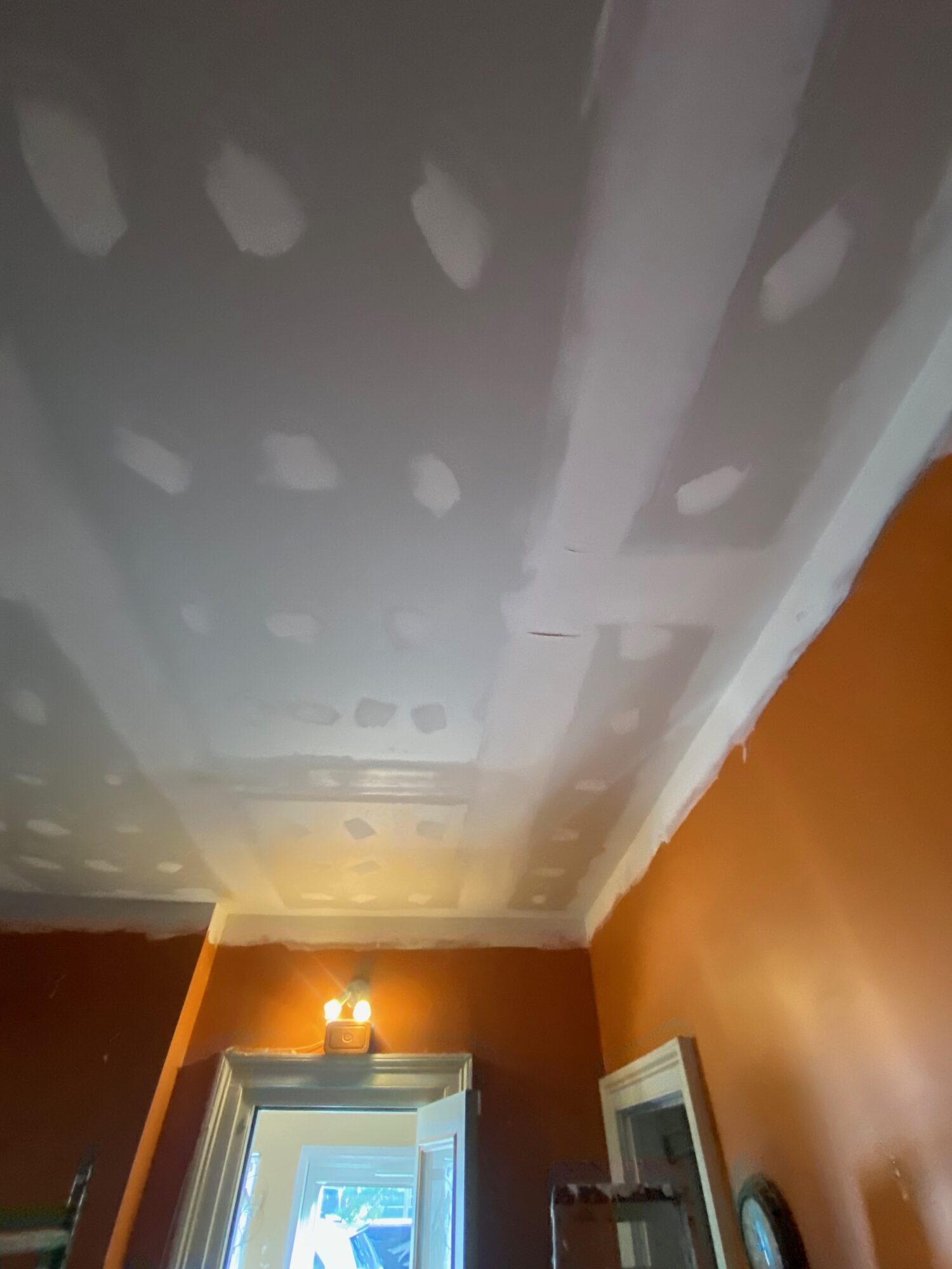 A ceiling hung with drywall, every screw spotted with compound and ready for taping.