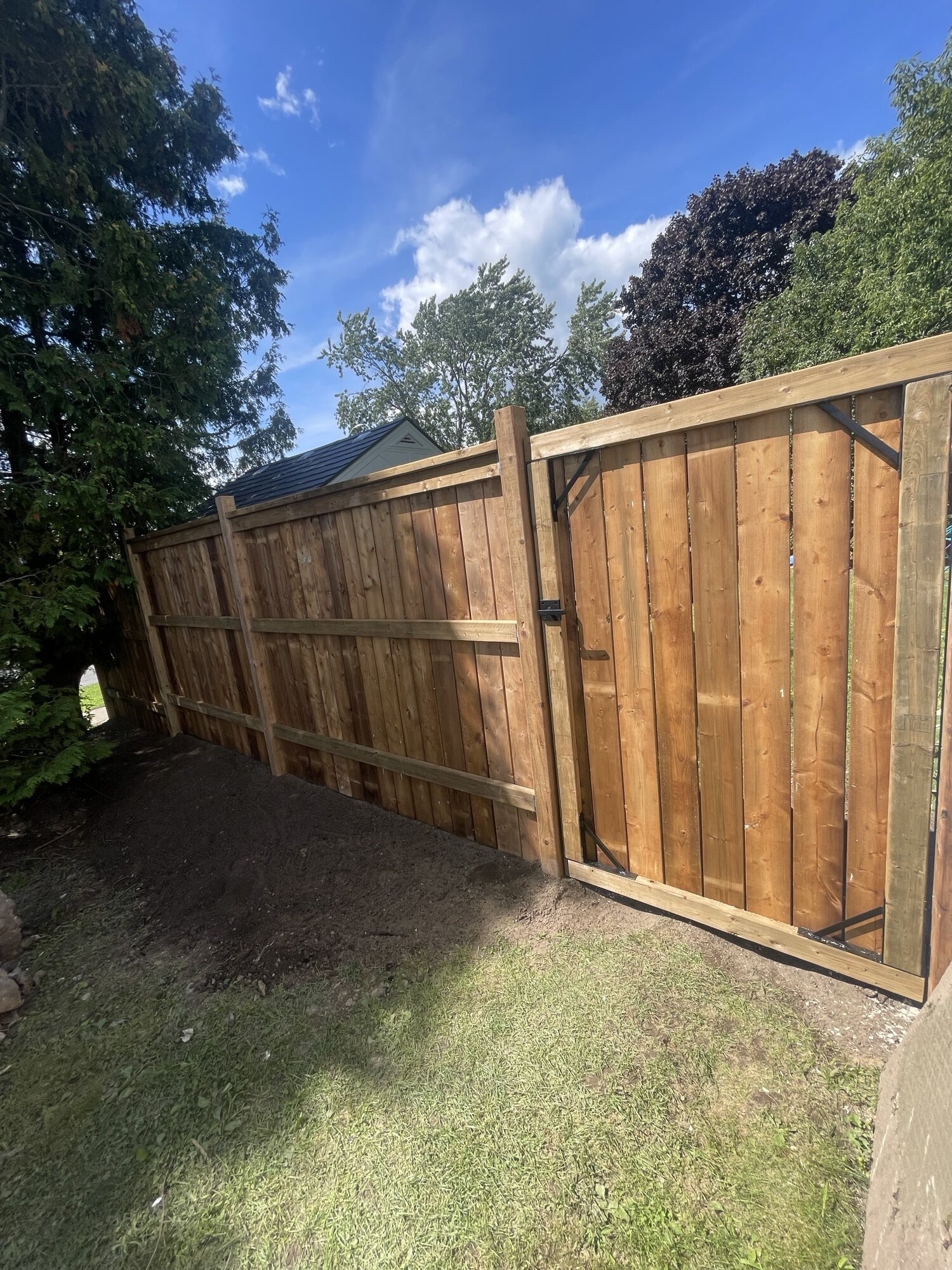 A new wood privacy fence with a matching gate on a lawn.