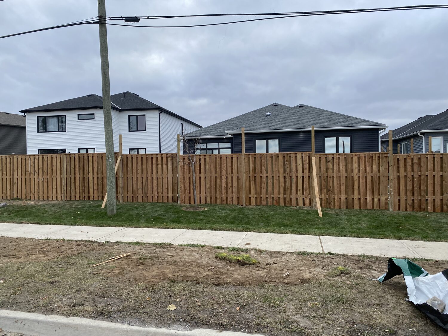 A new wood privacy fence running along a sidewalk in a new subdivision.