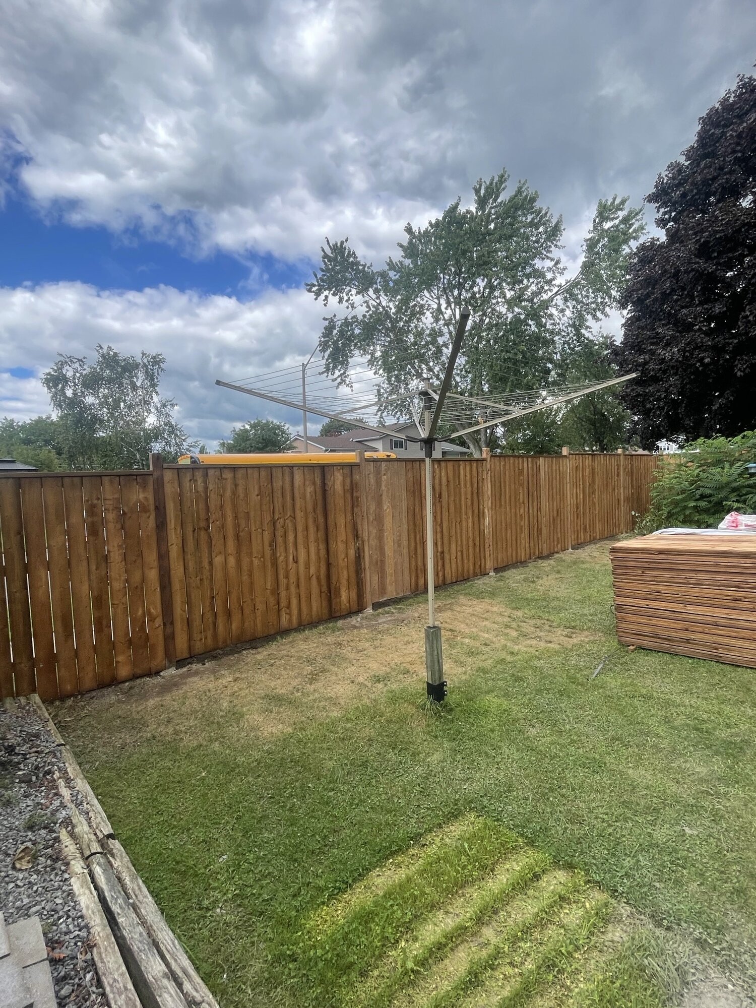 A new wood privacy fence running along the back of a lawn.