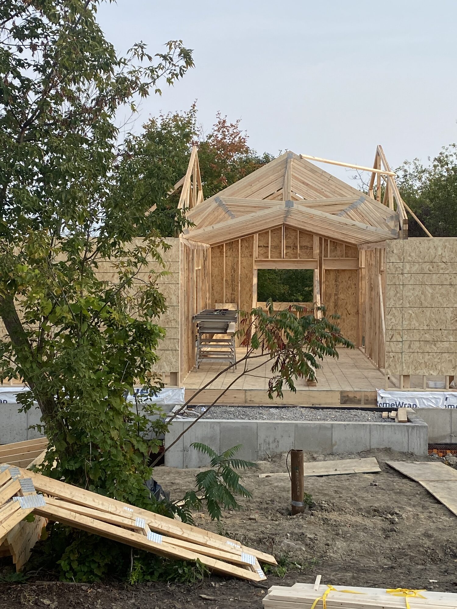 The gable end of a new building framed on its foundation, with the roof trusses braced above.