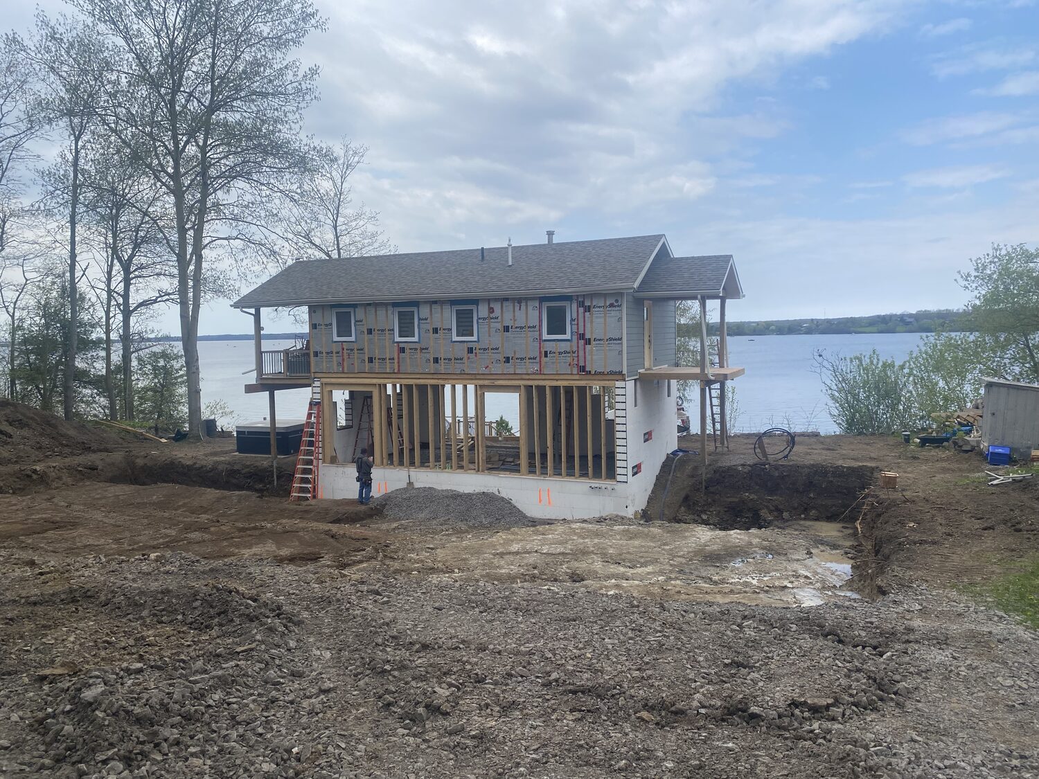 A two storey house on the water mid build, its new walkout level framed in on a dug out site.