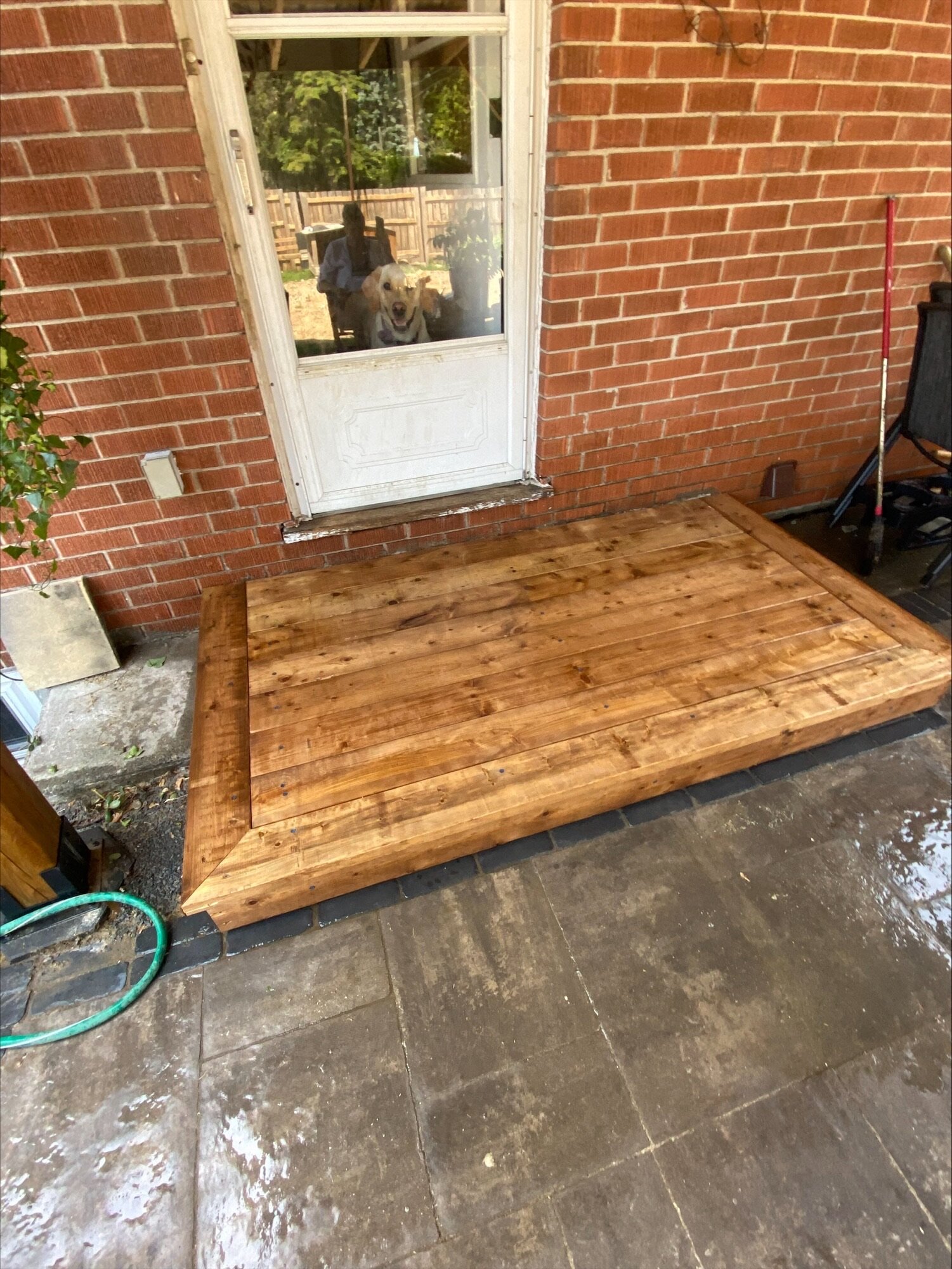 A new wood landing at the same back door, set on the patio stone.
