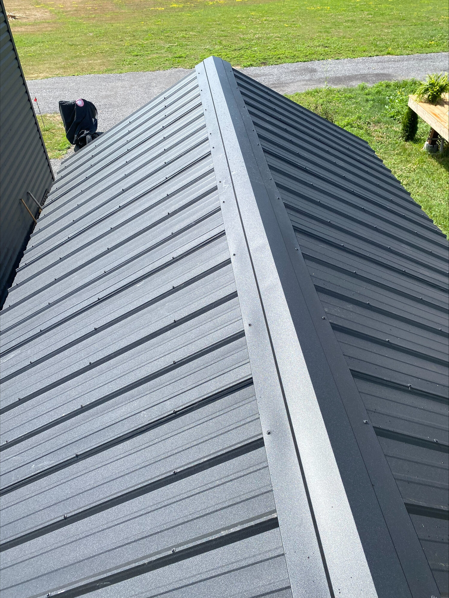 A new dark grey steel roof with its ridge cap fastened down.