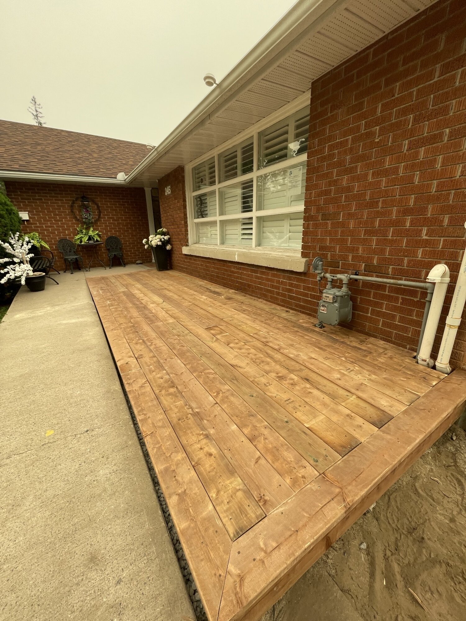 A new wood deck running the length of the same brick house.