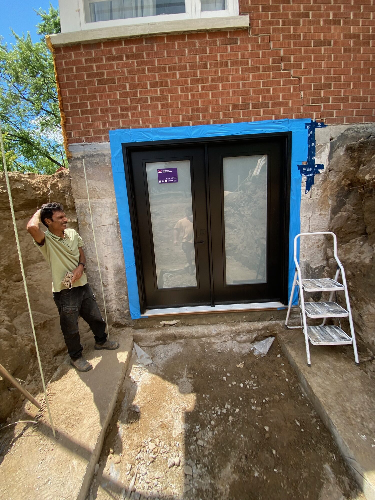 The same wall with the window opening cut down and a black double door set in.
