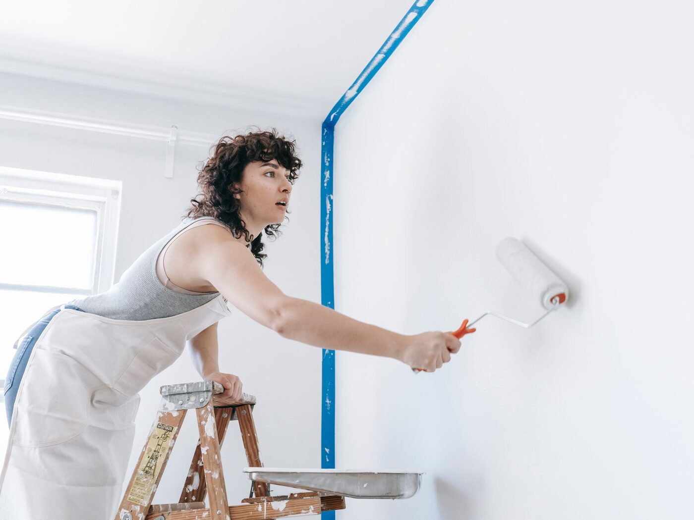 A painter rolling a fresh coat onto an interior wall.